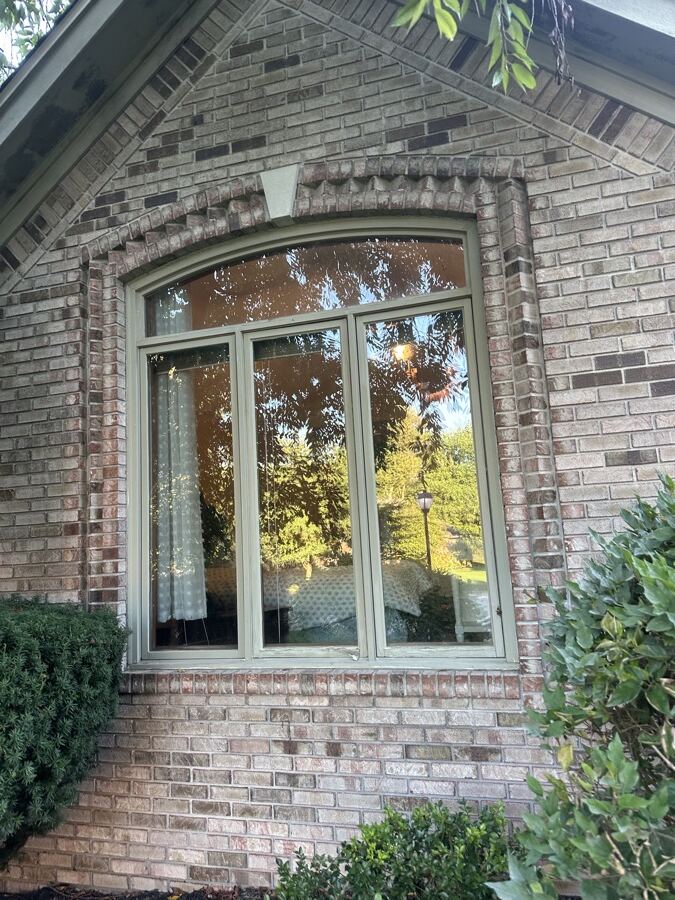 Old bronze-framed arched casement window before replacement