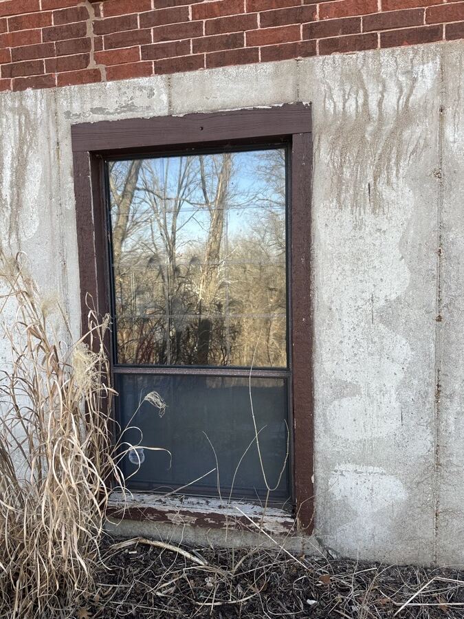 Old wood-framed basement window before replacement