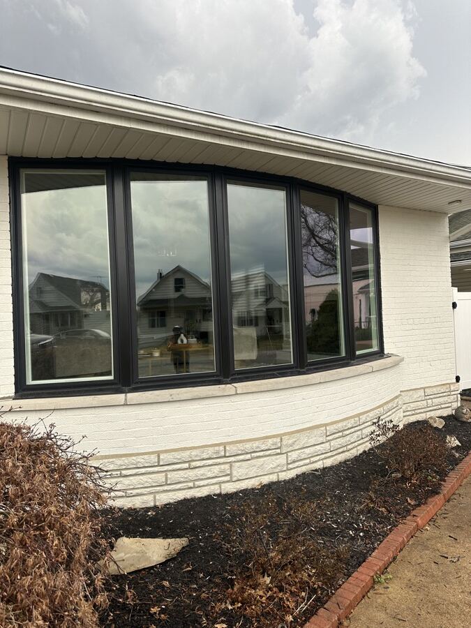 A black-framed bay window rebuilt pane by pane over a stone sill