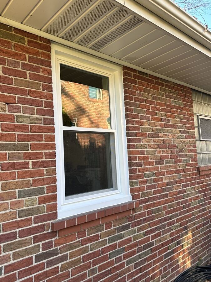 New white double-hung window on the same brick house after replacement