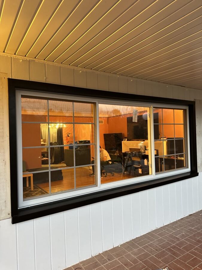 Porch wall with a new large black-framed picture window after replacement