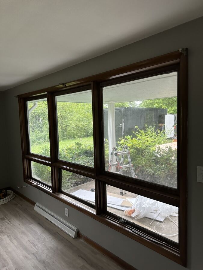 Interior view of an old window with worn dark wood trim before replacement