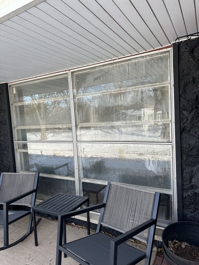 Old dirty aluminum awning windows on a stone-clad wall before replacement