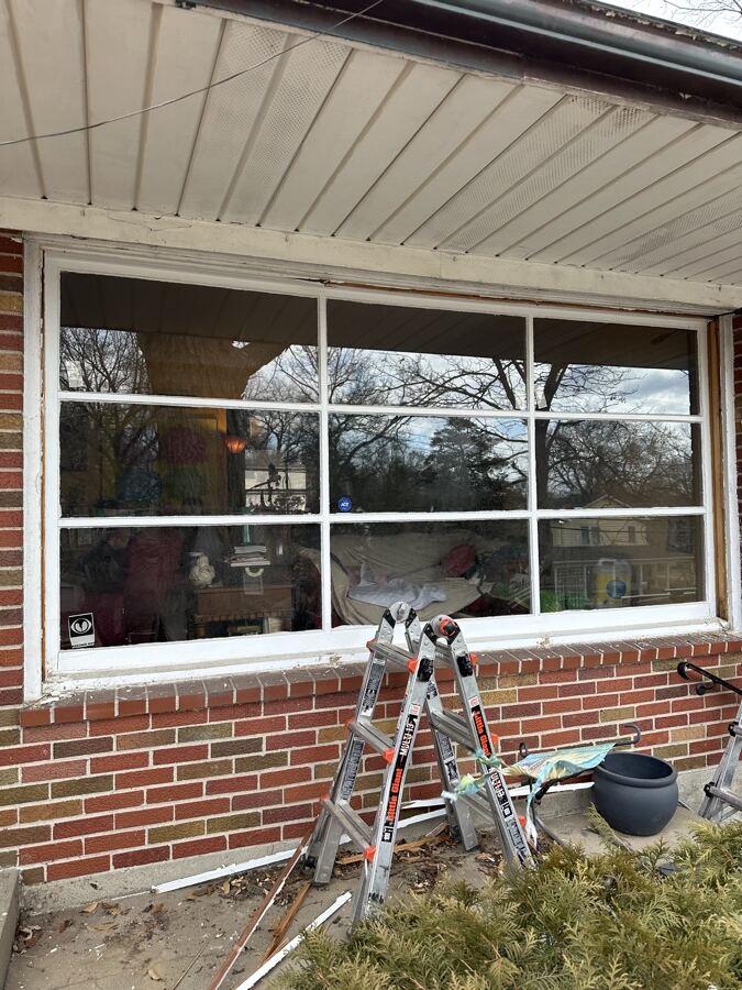 Old worn wood-framed triple window before replacement