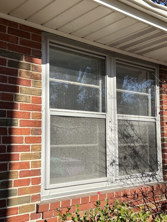Old aluminum windows with dirty screens before replacement