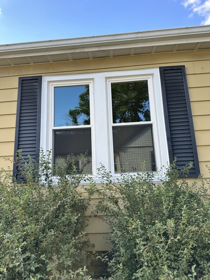 A white double-hung replacement set between the home’s original navy shutters